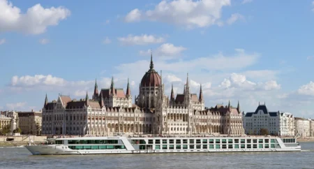 Una veduta del Danubio con in primo piano una nave da crociera e sullo sfondo la città di Budapest