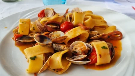 Cucina di mare napoletana, i piatti che portano il Golfo a tavola Calamarata con le vongole impiattati con pane bruschettato